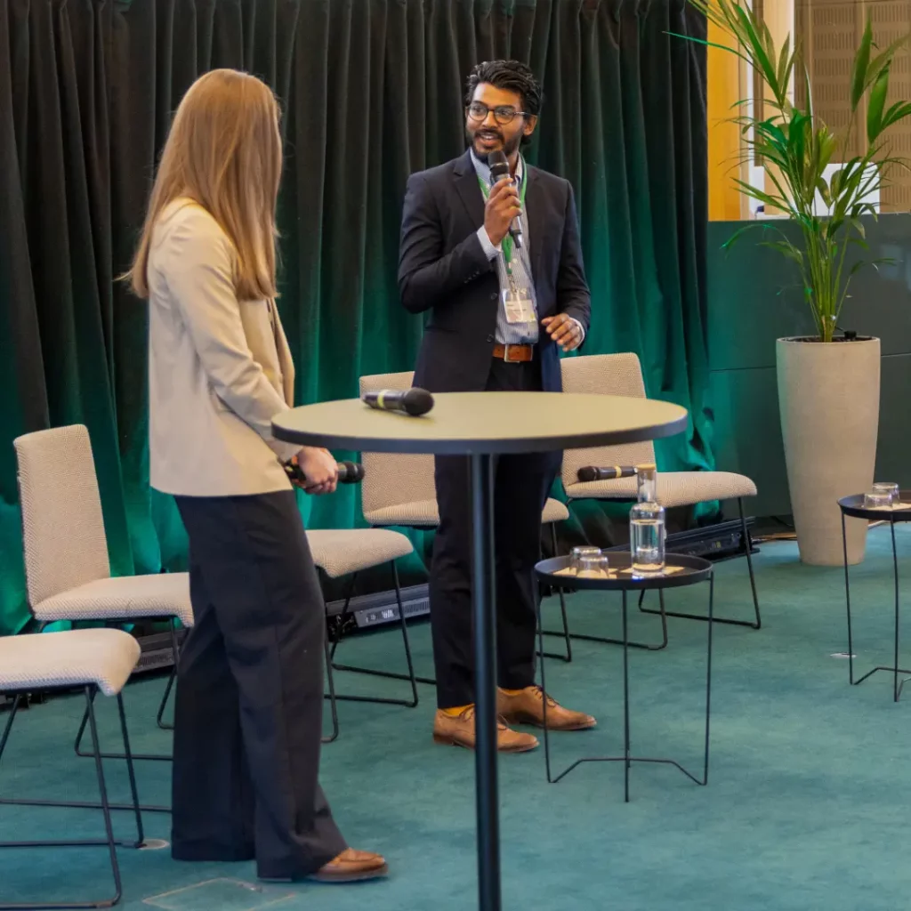 Two professionals discussing business strategies at a high-top table in a conference setting