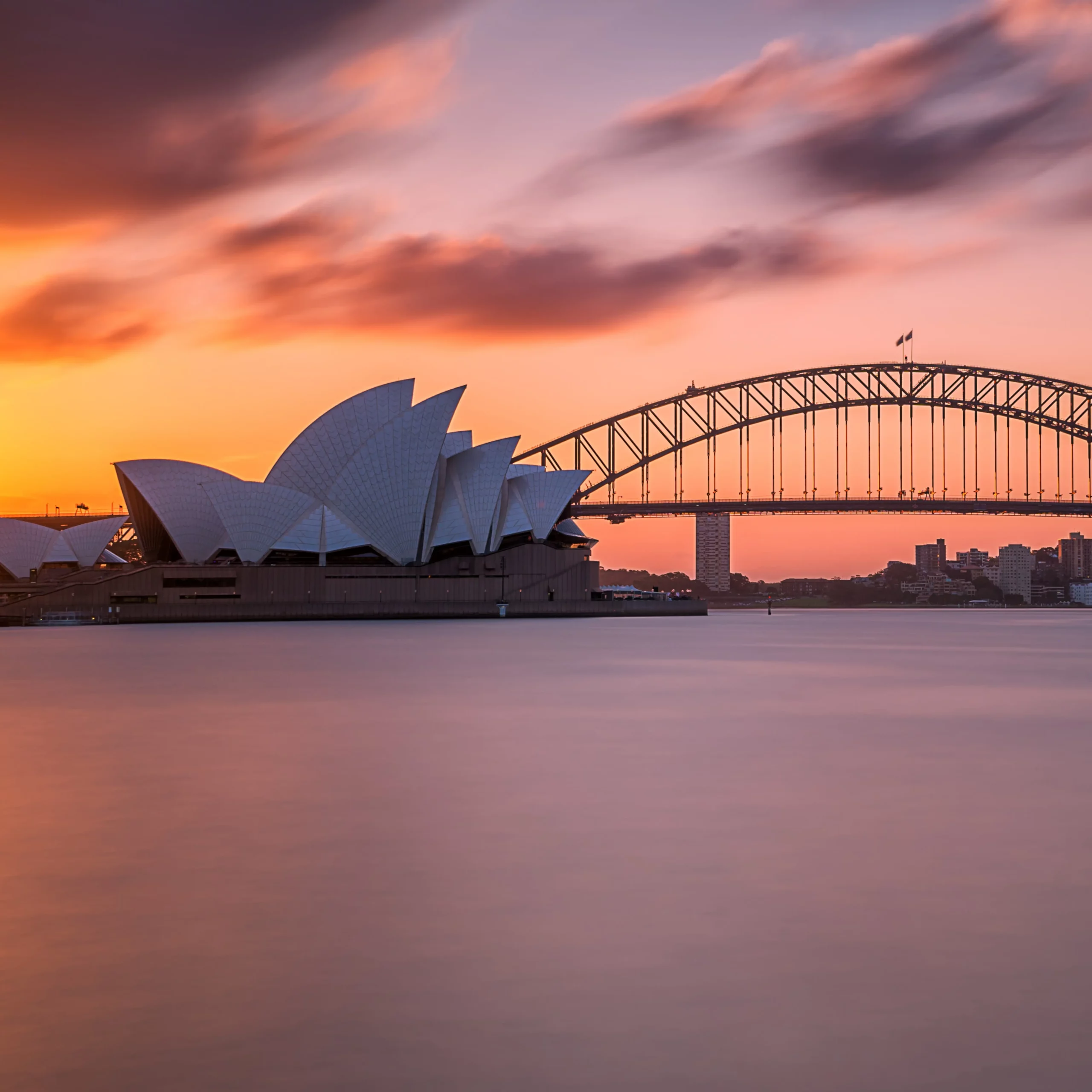 Sydney Opera House and Harbour Bridge illuminated by a colorful sunset sky