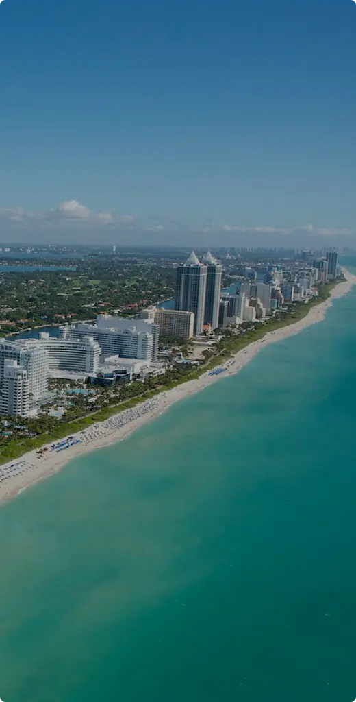 Aerial view of Miami coastline featuring beaches, high-rise buildings, and blue waters