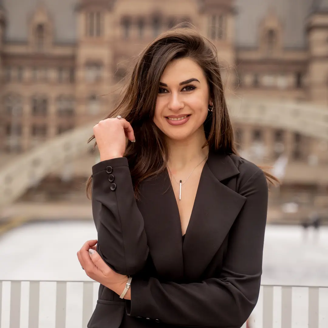 Professional woman smiling in a business suit, standing in front of a historic building